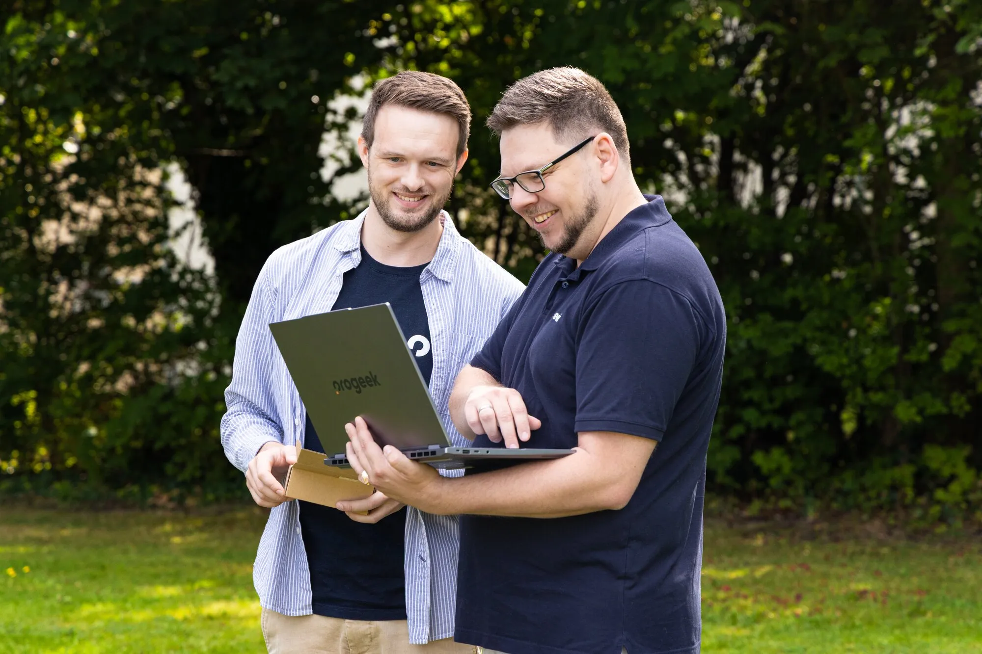 Zwei Mitarbeitende von PROGEEK sehen sich gemeinsam etwas auf einem Laptop an.